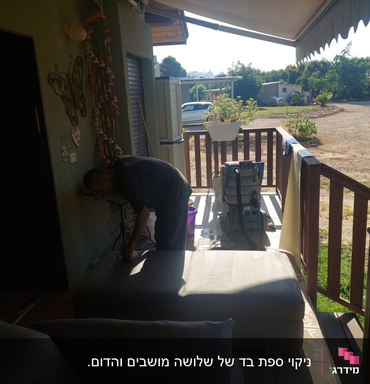 אדם מנקה ספה עם מכונת ניקוי במרפסת